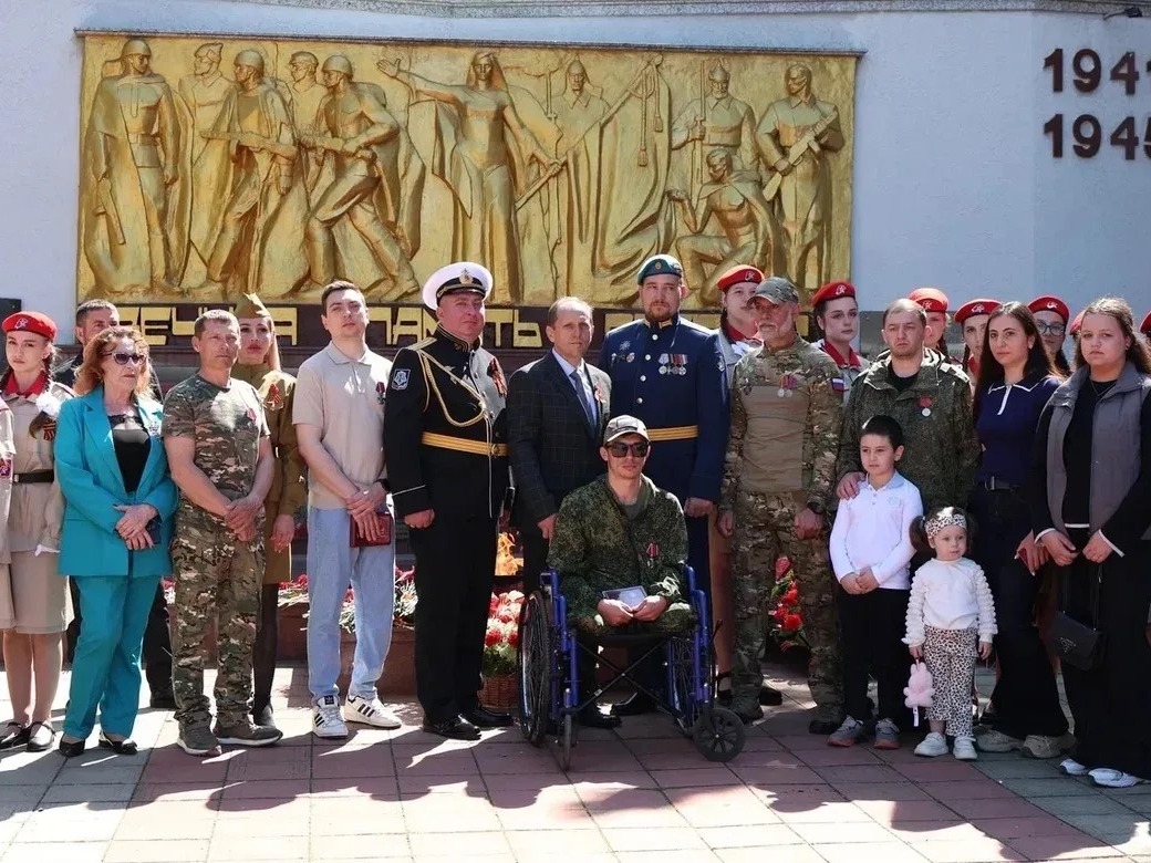 Глава с участниками встречи на на фоне стеллы.